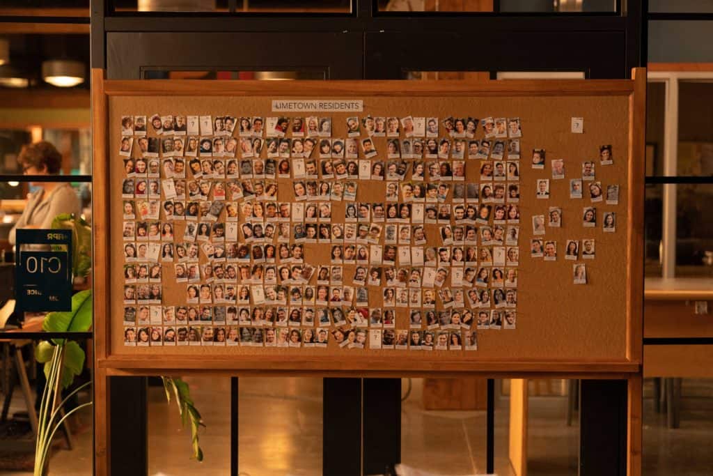 A corkboard in an office with dozens of photos of people pinned to it, labeled “LIMETOWN RESIDENTS” (credit: Facebook Watch)
